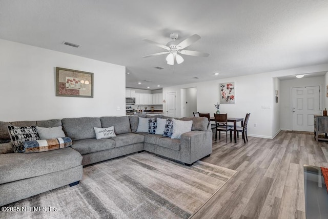 living room with light hardwood / wood-style flooring and ceiling fan