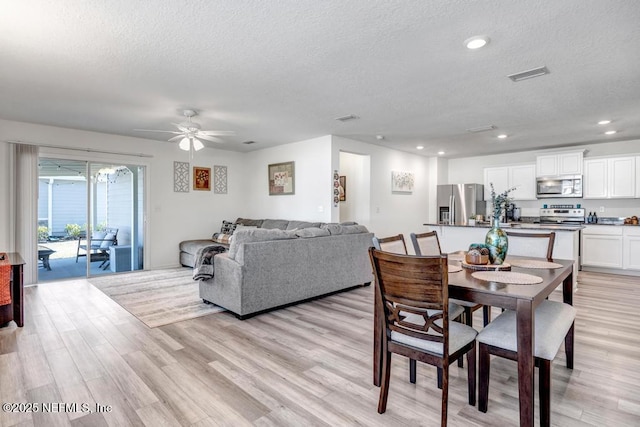 dining room with ceiling fan, a textured ceiling, and light wood-type flooring