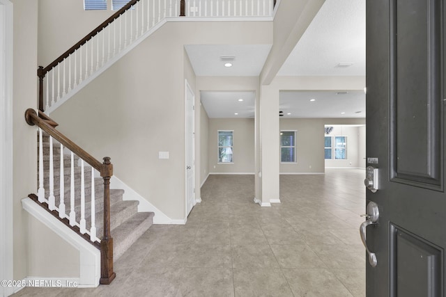 foyer entrance featuring light tile patterned floors, a towering ceiling, and a healthy amount of sunlight