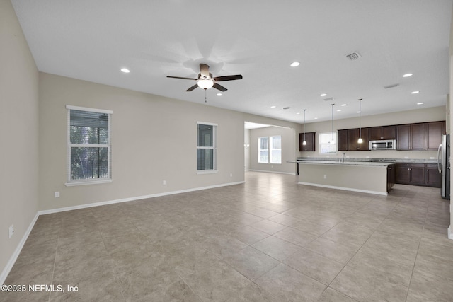 unfurnished living room featuring sink, light tile patterned floors, and ceiling fan