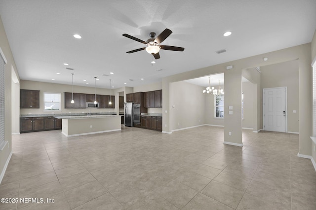 unfurnished living room with ceiling fan with notable chandelier and light tile patterned floors