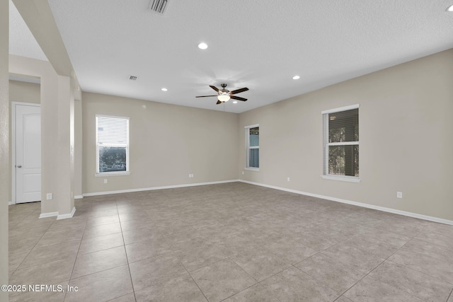 tiled empty room featuring ceiling fan and a textured ceiling