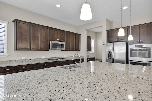 kitchen with pendant lighting, appliances with stainless steel finishes, and light stone countertops