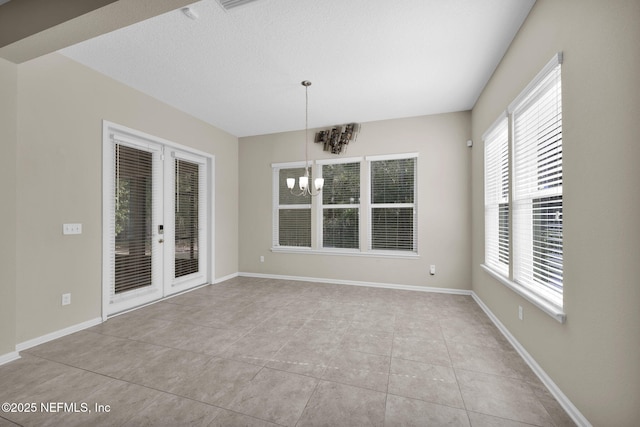 unfurnished dining area featuring a notable chandelier, light tile patterned floors, and french doors