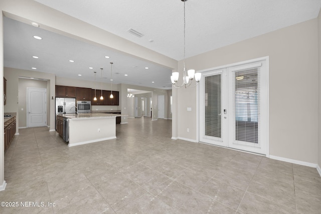 kitchen featuring sink, a kitchen island with sink, hanging light fixtures, stainless steel appliances, and a chandelier