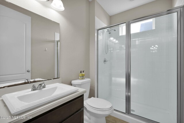 bathroom featuring vanity, a shower with door, and toilet