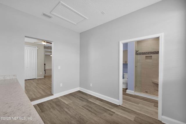 unfurnished bedroom with wood-type flooring, ensuite bathroom, and a closet