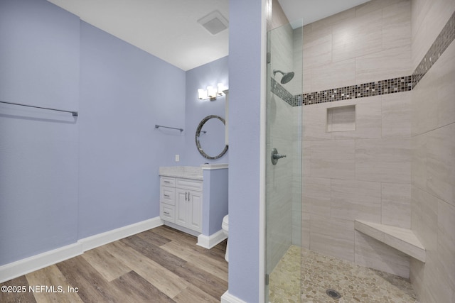 bathroom with vanity, a tile shower, hardwood / wood-style floors, and toilet