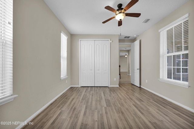 unfurnished bedroom featuring light hardwood / wood-style floors, a closet, and ceiling fan