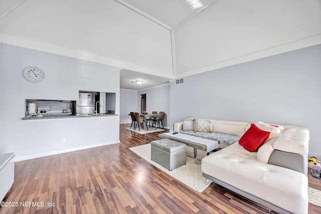 living room with a towering ceiling, wood-type flooring, and sink