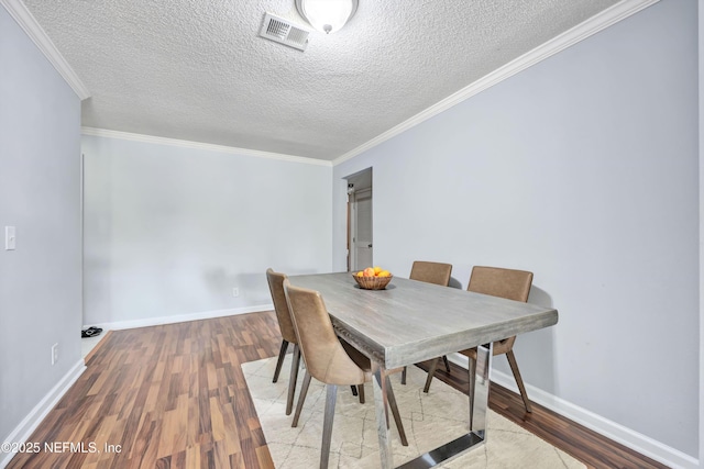 dining space featuring crown molding, light hardwood / wood-style flooring, and a textured ceiling