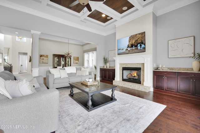 living room with a towering ceiling, dark hardwood / wood-style flooring, ornamental molding, coffered ceiling, and a brick fireplace