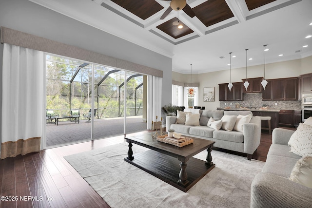 living room with crown molding, light wood-style floors, coffered ceiling, and a healthy amount of sunlight