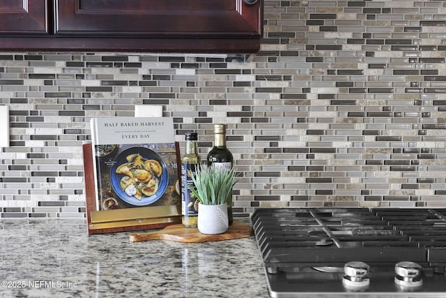 room details with backsplash, light stone countertops, and stovetop