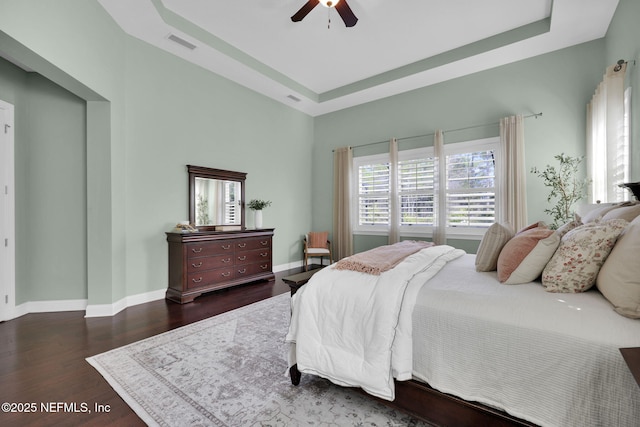 bedroom featuring a tray ceiling, dark hardwood / wood-style floors, and ceiling fan