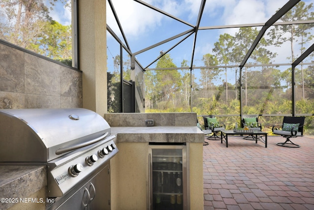 view of patio featuring wine cooler, a grill, glass enclosure, and an outdoor kitchen