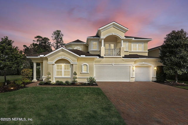 mediterranean / spanish house featuring decorative driveway, an attached garage, a front lawn, and stucco siding