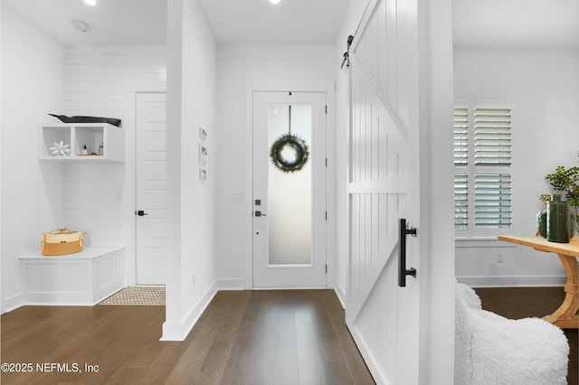 foyer entrance with a barn door and dark hardwood / wood-style floors