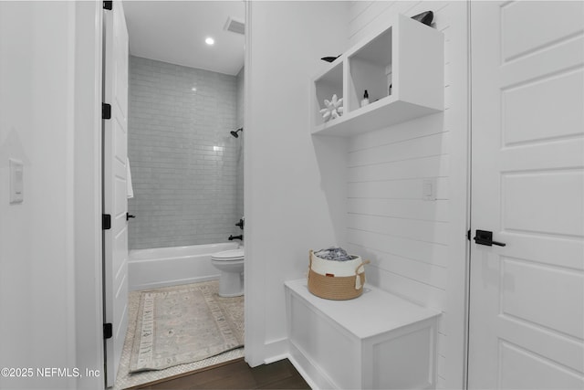 bathroom featuring toilet and tiled shower / bath combo