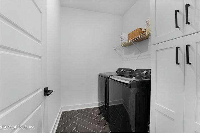 laundry room with cabinets, washing machine and clothes dryer, and dark tile patterned floors