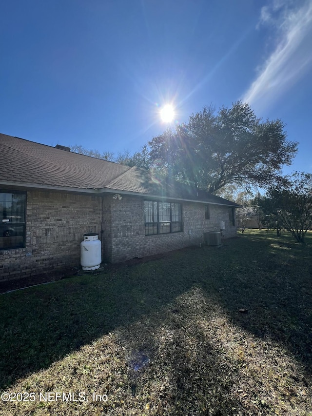 view of side of property featuring cooling unit and a yard