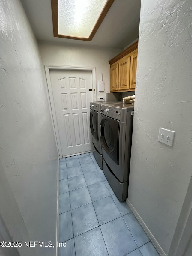 washroom with light tile patterned flooring, cabinets, and washer and dryer