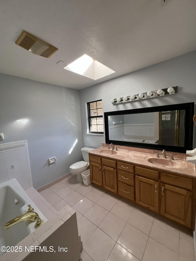 bathroom featuring toilet, a skylight, vanity, a bathtub, and tile patterned flooring