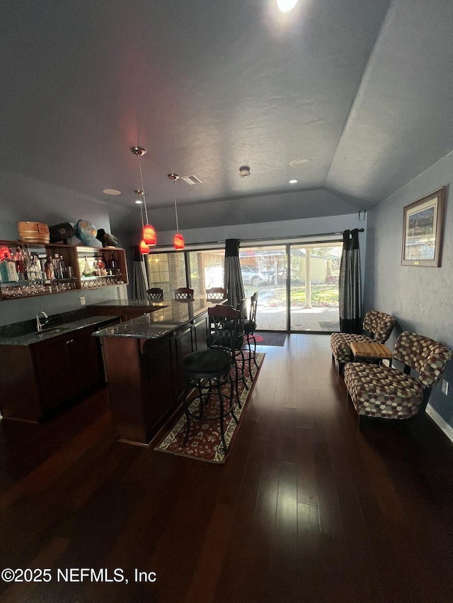 kitchen with a kitchen island, pendant lighting, lofted ceiling, dark brown cabinetry, and dark wood-type flooring