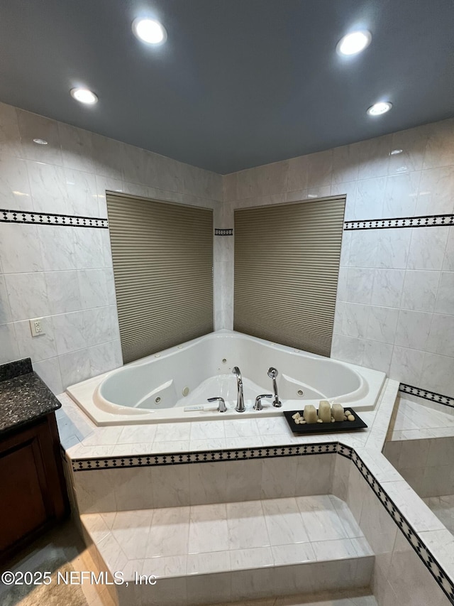 bathroom with vanity, tiled bath, and tile walls