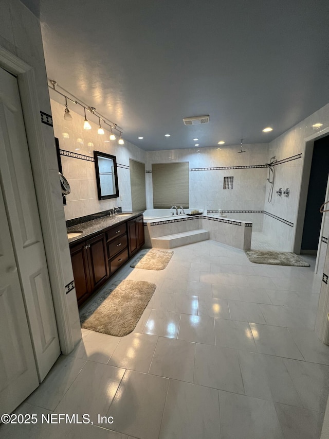 bathroom featuring tile patterned floors, vanity, shower with separate bathtub, and tile walls