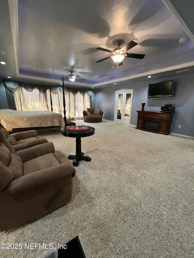 living room with a raised ceiling, carpet, ceiling fan, and french doors