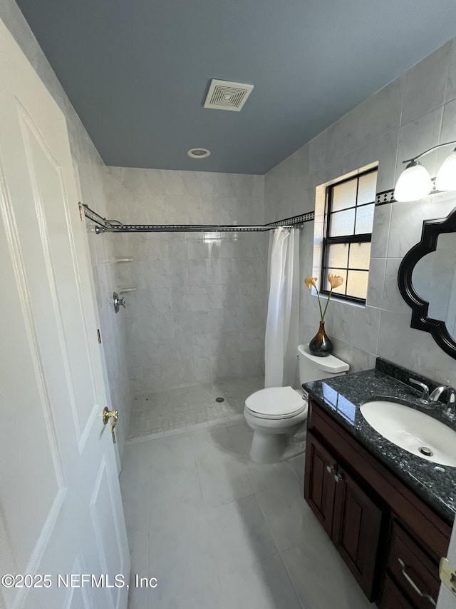 bathroom featuring vanity, toilet, tile walls, and walk in shower