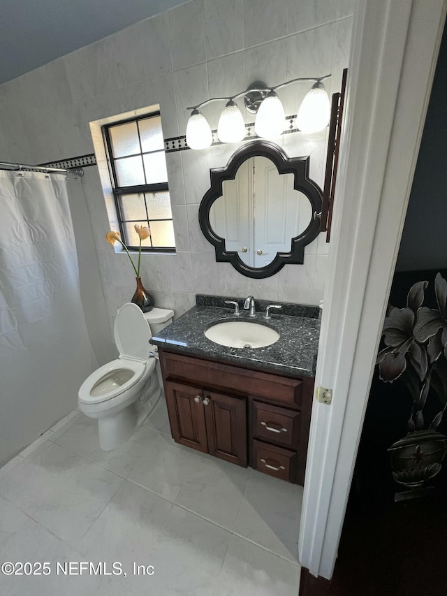 bathroom with vanity, toilet, and tile walls