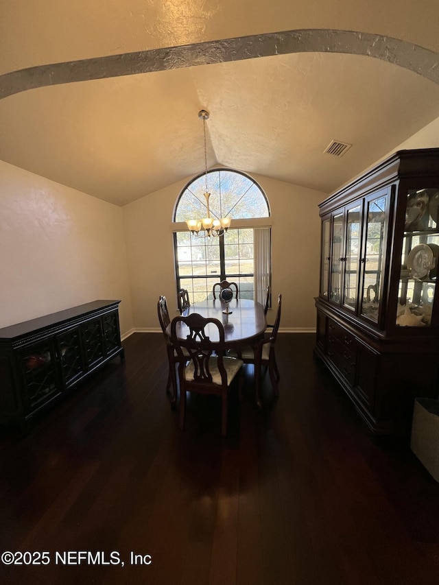 dining room with a notable chandelier, dark wood-type flooring, and vaulted ceiling