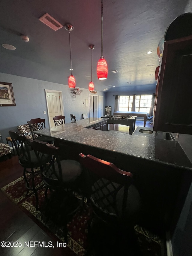 kitchen with hardwood / wood-style flooring, decorative light fixtures, and kitchen peninsula