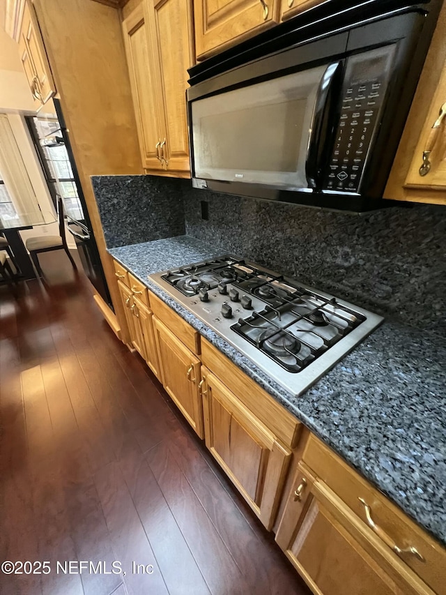 kitchen featuring backsplash, dark stone counters, and stainless steel gas stovetop