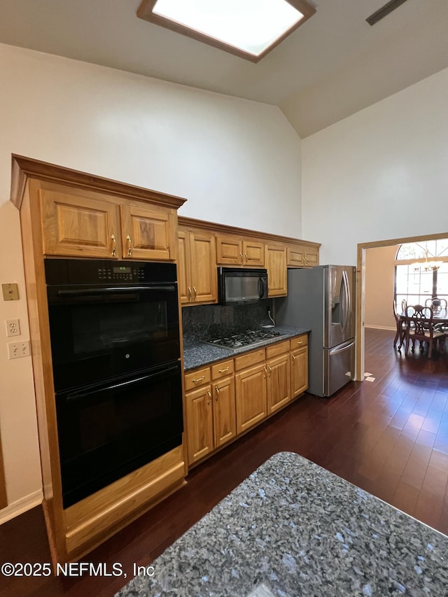 kitchen featuring black appliances, high vaulted ceiling, dark stone countertops, dark hardwood / wood-style floors, and backsplash