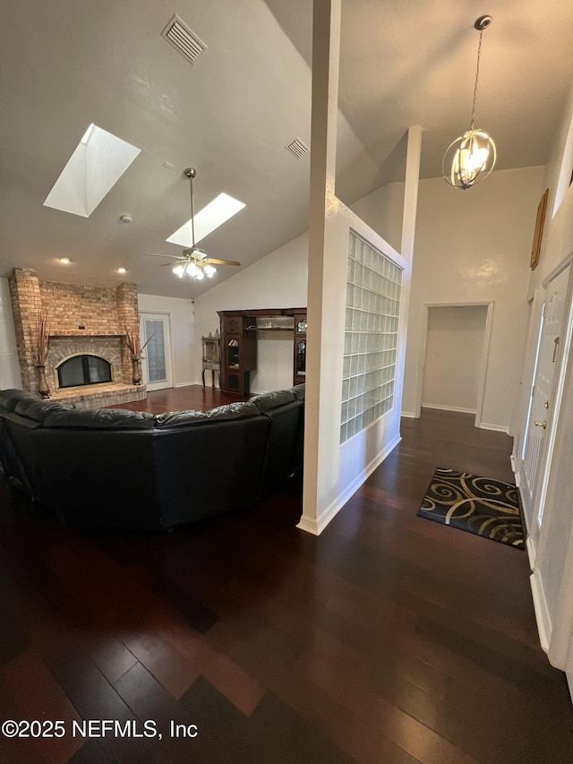 living room featuring a brick fireplace, dark hardwood / wood-style floors, and a skylight