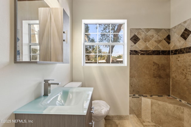 bathroom featuring vanity, toilet, and a tile shower