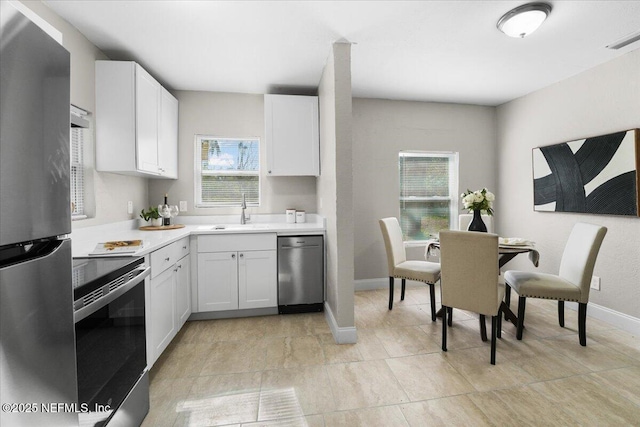 kitchen featuring a healthy amount of sunlight, appliances with stainless steel finishes, sink, and white cabinets