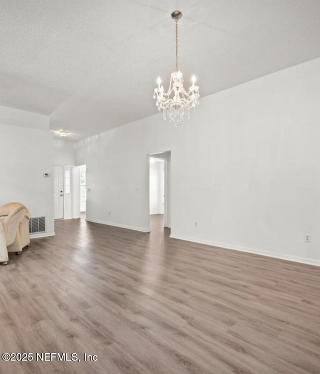 unfurnished living room with a notable chandelier, wood-type flooring, and a textured ceiling