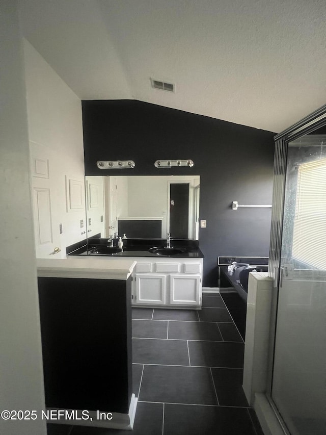 bathroom with tile patterned floors, vanity, separate shower and tub, and vaulted ceiling