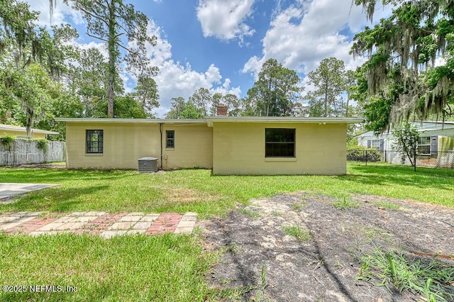 rear view of property featuring a yard and central air condition unit