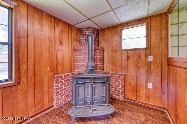 details featuring wood-type flooring, a wood stove, a drop ceiling, and wooden walls