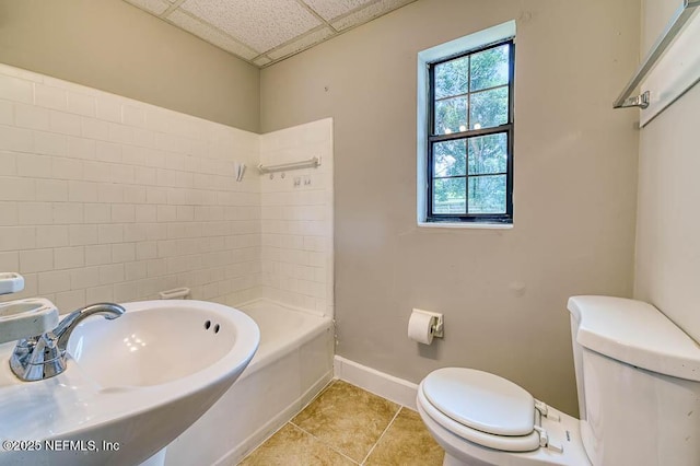 full bathroom featuring tile patterned floors, toilet, bathing tub / shower combination, sink, and a drop ceiling