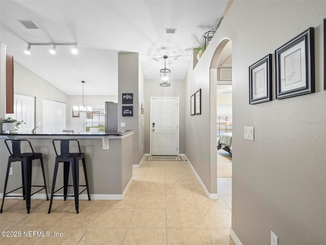 kitchen with pendant lighting, light tile patterned floors, lofted ceiling, a breakfast bar area, and kitchen peninsula