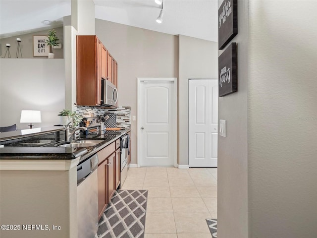 kitchen featuring sink, tasteful backsplash, vaulted ceiling, light tile patterned floors, and appliances with stainless steel finishes