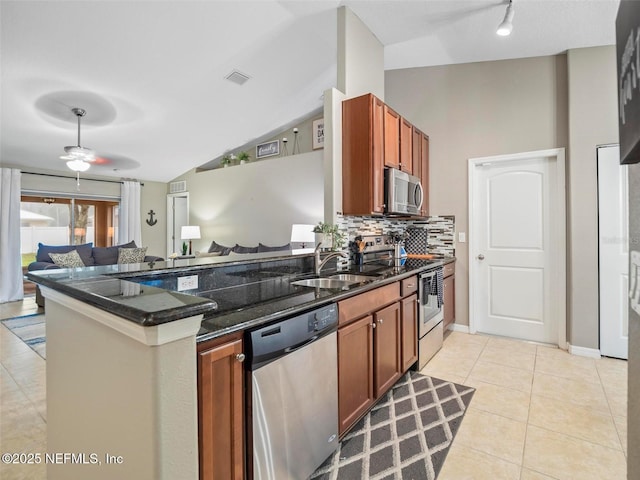 kitchen featuring sink, light tile patterned floors, dark stone countertops, kitchen peninsula, and stainless steel appliances