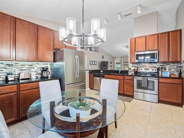 kitchen with lofted ceiling, sink, decorative light fixtures, appliances with stainless steel finishes, and decorative backsplash