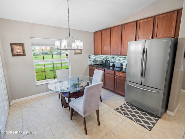 kitchen featuring vaulted ceiling, stainless steel refrigerator, backsplash, hanging light fixtures, and an inviting chandelier